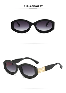 Detailed close-up of oval black sunglasses with gradient lenses and gold metal temple accents