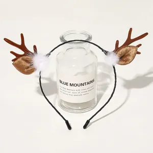 Detail of plush reindeer antler headband with golden ears and soft faux fur pom-poms