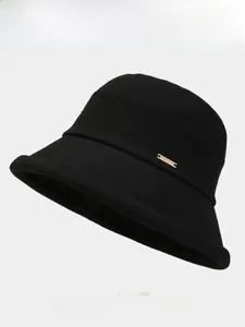Gros plan détaillé d'un chapeau bob noir montrant la texture sergé et le logo doré