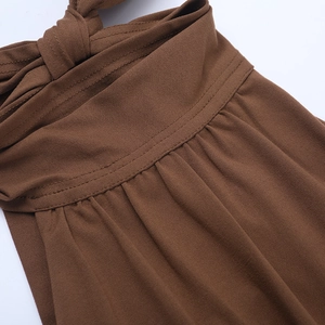 Détail du nœud et des coutures fines sur une robe dos nu marron avec un tissu fluide