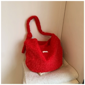 Detailed view of red plush tote bag fabric texture with soft faux fur and white woven label