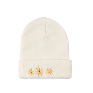 Close-up of three golden and red embroidered floral patterns on a white knit beanie