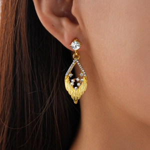 Detail of a gold leaf earring with shimmering rhinestones worn by a model