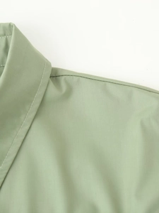 Detailed close-up showing the collar stitching and woven texture of the light green shirt