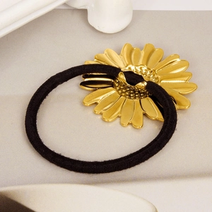 Detailed close-up of a golden daisy metal ornament on a black elastic hair tie