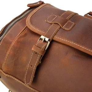 Detail of vintage brown leather bag showing white stitching and metal buckle texture