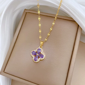 Macro shot of gold four-leaf flower necklace with purple zircon and micro-pave crystals