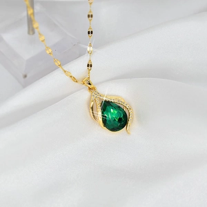 Elegant gold-tone teardrop necklace with a large green gemstone on white silk fabric