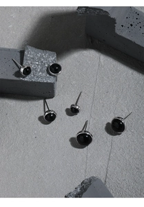 Detailed view of round black onyx stud earrings in S925 sterling silver on stone surface