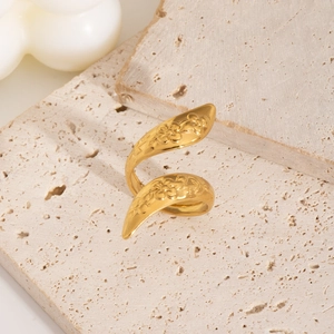 Snake shaped adjustable gold ring with floral embossing on textured stone background