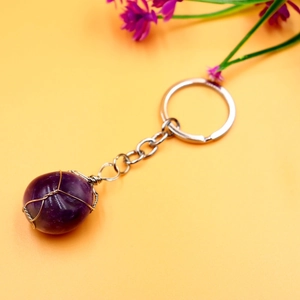 Detail of copper wire wrapped dark purple natural stone on a sleek metal keychain