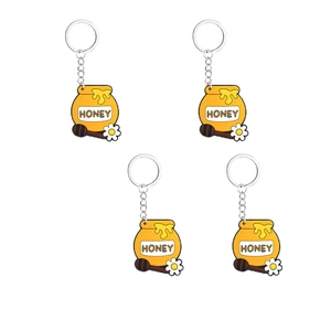 Dettaglio di quattro portachiavi in PVC a forma di barattolo di miele giallo con margherita