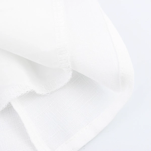 Dettaglio dell'orlo dell'abito floreale bianco con cuciture di pregio e tessuto a trama
