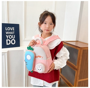 Close-up of a pink cartoon rabbit backpack worn by a girl with blue carrot details