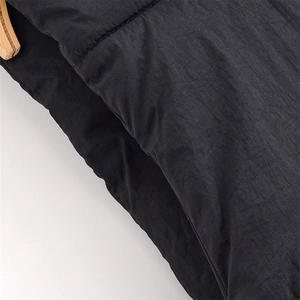 Close-up of black polyester vest fabric texture with wooden hanger on white background