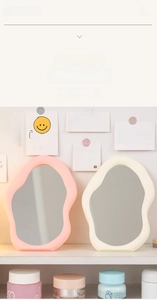 Close-up of wavy irregular vanity mirror on a white shelf with decorative props