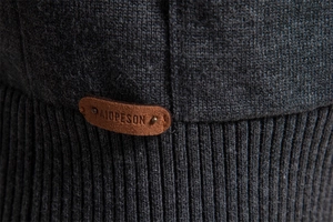 Macro detail of dark grey knit fabric texture with a premium brown leather logo patch