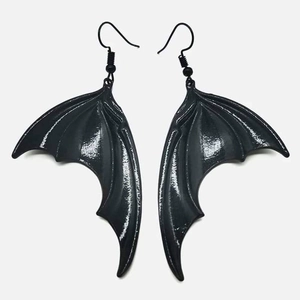 Gros plan détaillé des boucles d'oreilles gothiques ailes de chauve-souris noires