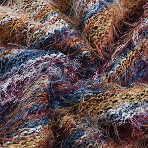 Vue macro d'un tissu en maille multicolore montrant la texture pelucheuse et le fil bleu orange