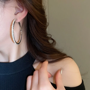 Close-up of a silver-toned hoop earring with sparkling rhinestones worn by a model
