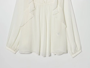 Detailed view of ruffle layers and pleated texture on white chiffon blouse