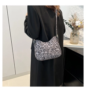 Chic leopard print crossbody bag styled on shoulder with black strap and metallic hardware