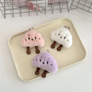 Dettaglio macro di tre portachiavi a nuvola di peluche in rosa, bianco e viola