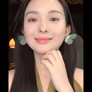 Gros plan de boucles d'oreilles ailes de papillon vertes portées pour un look de vacances