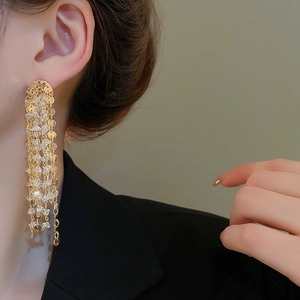 Detail of 18k gold plated long tassel earrings with crystals worn by a model