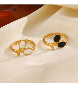 Macro detail of 18K gold plated leaf ring with black and white enamel on beige silk