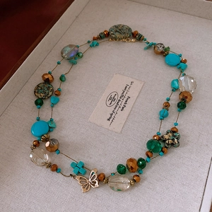 Close-up of bohemian layered necklace with turquoise beads and gold butterfly pendant