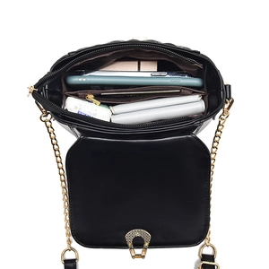 Minimalist black quilted chain bag showing internal compartments with phone and wallet