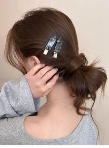 Detail of dark grey marble patterned acetate hair clips with rhinestones on model's hair