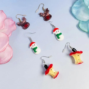 Three pairs of cute Christmas earrings featuring reindeer, snowman, and apple designs