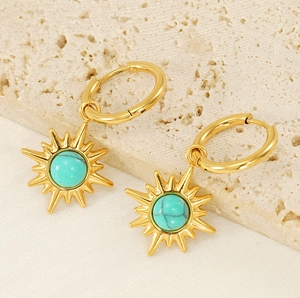 Detailed view of gold hoop earrings with turquoise sunburst charms on stone background