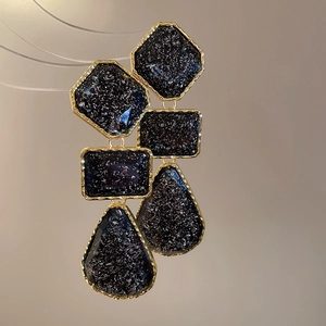 Close-up of vintage resin geometric drop earrings with gold frames and black stones