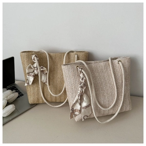 Détail de sacs cabas en paille tressée avec poignées en corde et foulards décoratifs