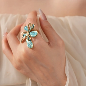 Close-up of vintage gold flower ring with blue enamel petals worn by a model