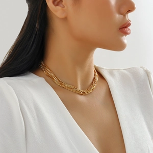 Close-up of layered gold chain necklace featuring geometric sphere charm on model