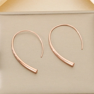 Detail of rose gold curved line earrings with a polished finish and minimalist hook design
