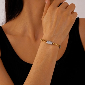 Dettaglio del bracciale a catena dorata con ciondolo ovale in pavé di diamanti