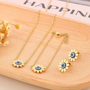 Detail of golden sunflower jewelry set featuring blue evil eye charms on a wood tray