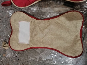 Detail of bone-shaped burlap Christmas stocking with red trim and white patch name tag