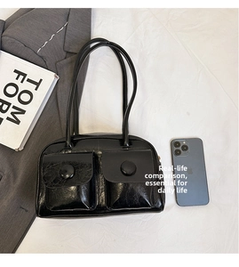 Detail of black glossy PU leather shoulder bag with double pockets and round buckles
