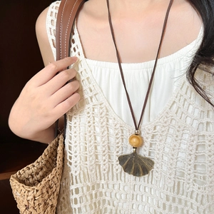 Bohemian long necklace featuring a metallic ginkgo leaf pendant and wooden bead on suede cord