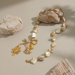 Detailed view of ocean theme necklace with shell pendants and lobster charm on stones