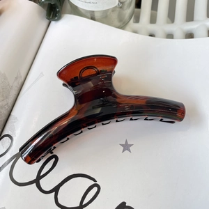 Detailed view of amber tortoiseshell hair claw clip on aesthetic magazine background