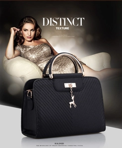 Detail of black embossed leather handbag featuring elegant golden deer charm pendant