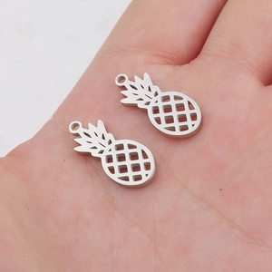 Close-up of two hollow pineapple charms in silver stainless steel held in a palm