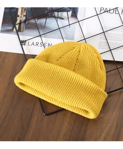 Close-up of vibrant yellow knitted beanie with thick texture on a wooden desk